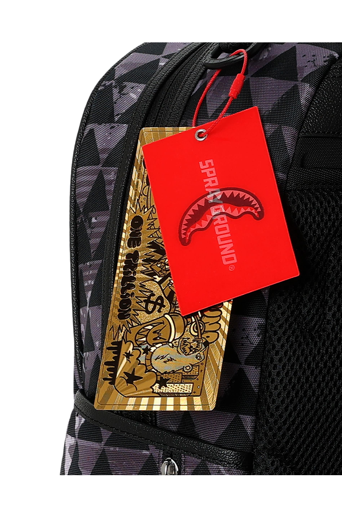 A close-up of a backpack with a black and gray geometric pattern, featuring a bright red 'SPRAYGROUND' hangtag and a gold tag attached to the zipper.
