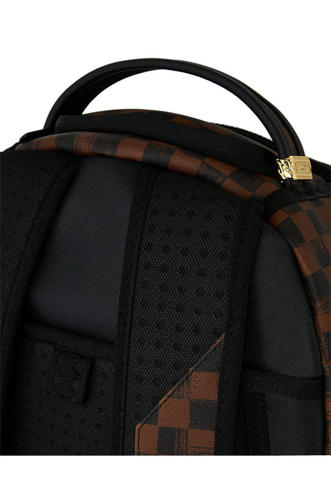 Close-up of the back of a black backpack with brown and black checkered patterned fabric panels and a small gold-tone brand plaque.