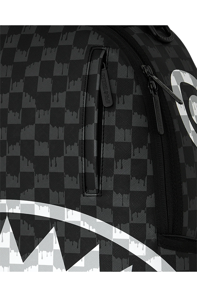 Close-up of a black and gray checkered backpack with a shark-mouth graphic in white and gray, showing a vertical zippered pocket and side zipper.