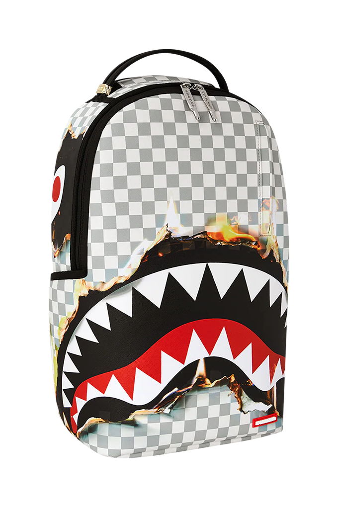 A Sprayground Shark backpack featuring a black and white checkered pattern, a large black shark mouth graphic with white, red, and black teeth, and a burning effect across the middle, shown on a plain white background.