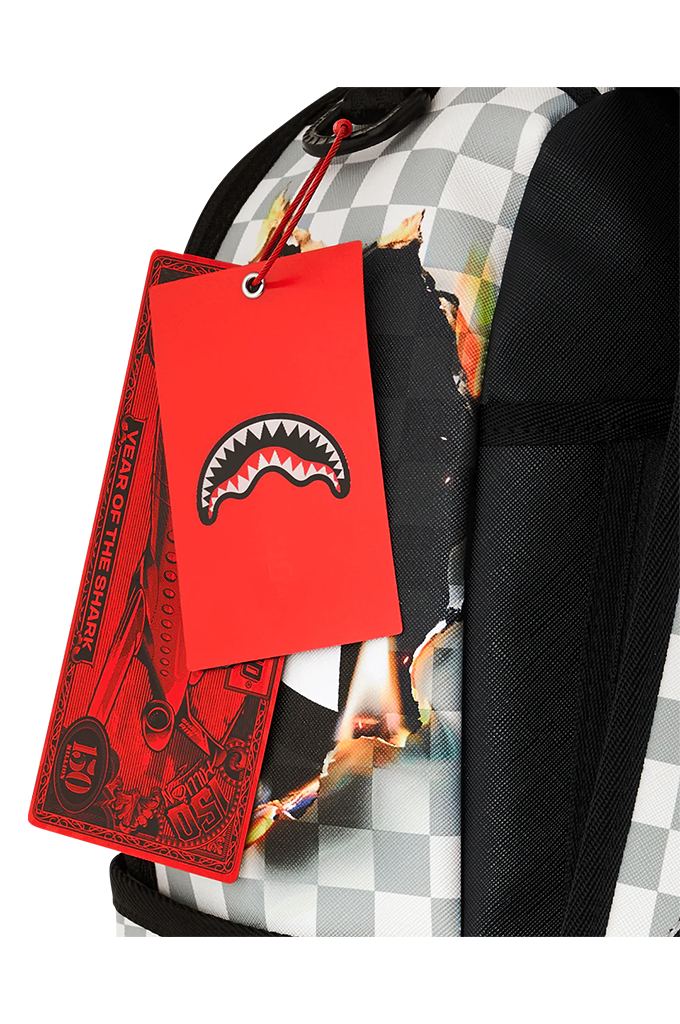 Close-up of a backpack with a red Shark Mouth hangtag featuring the shark mouth logo, next to a black and white checkered pattern and a black mesh side pocket.