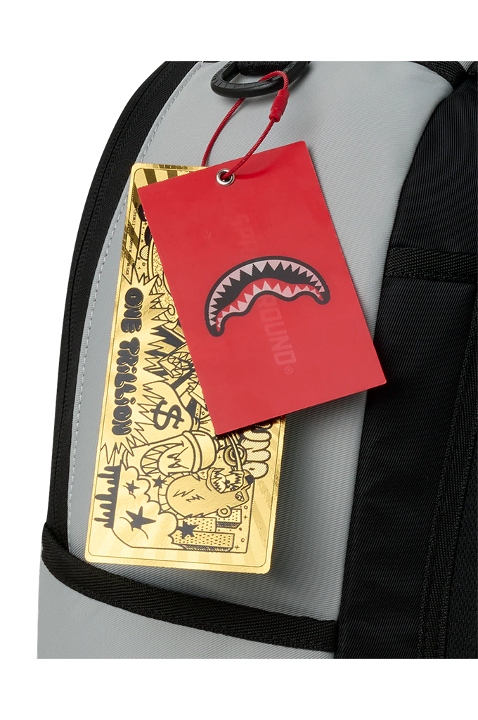 Close-up of a gray and black backpack with a red Sprayground brand hangtag and a gold metal keychain tag attached.