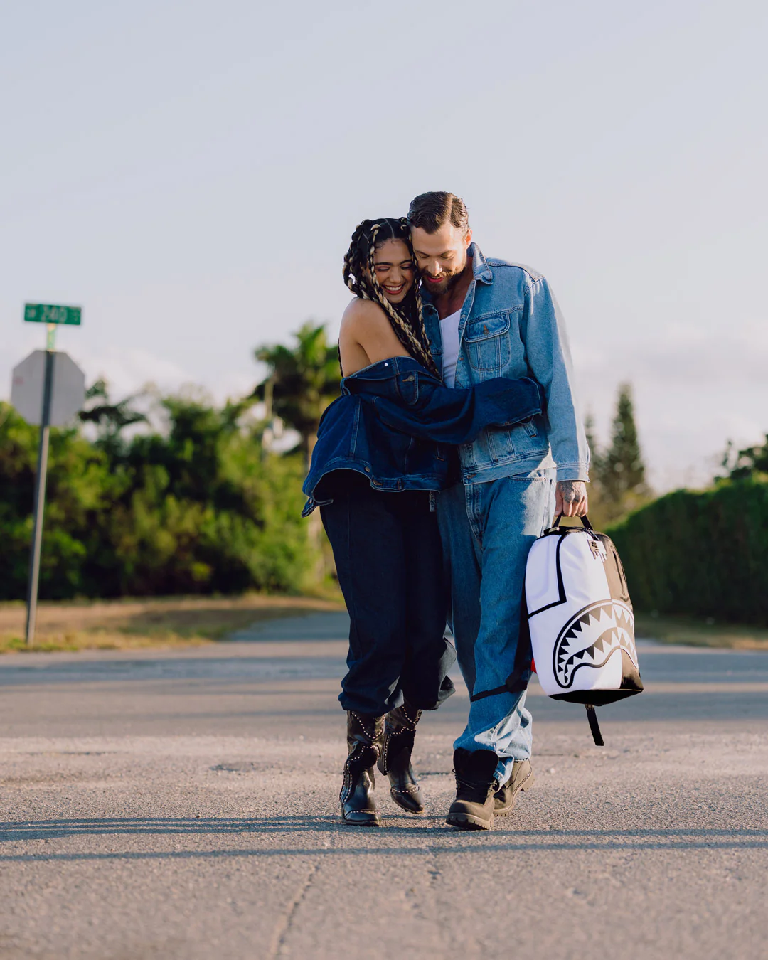 Two people walking on a road with a white and black bag.