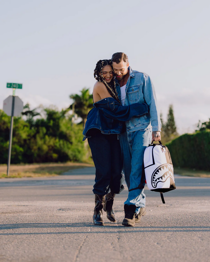 Two people walking on a road with a white and black bag.