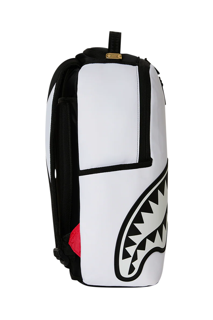 A white and black backpack featuring a shark mouth graphic on the front, with a small red accent on the side and a gold brand tag near the top handle.