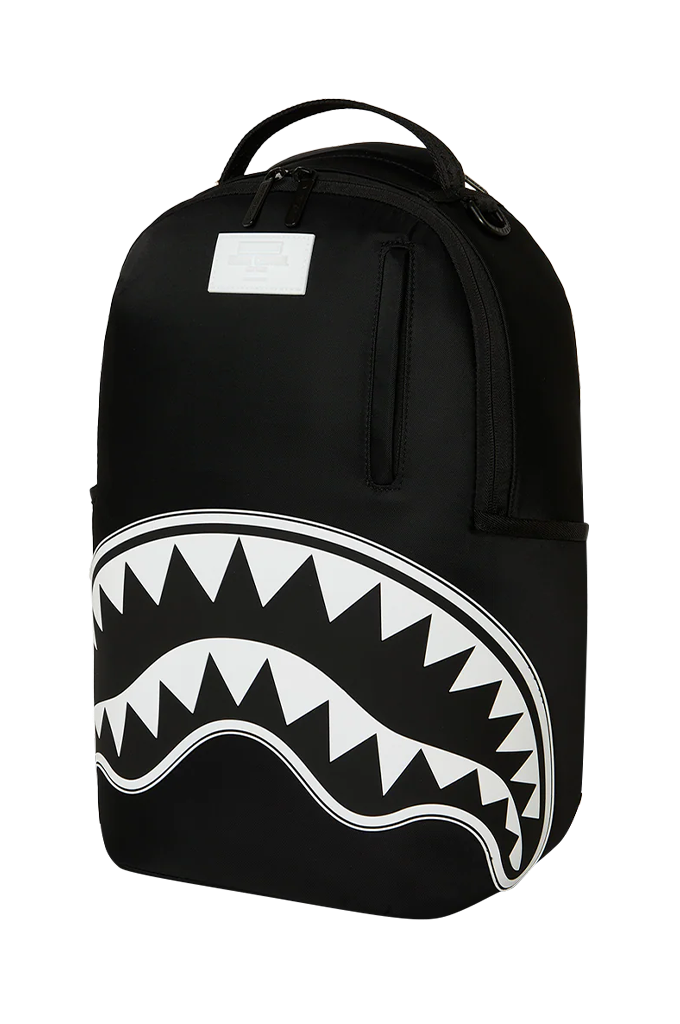 A black backpack featuring a large white shark mouth graphic on the lower front, with a top carry handle and a blank white rectangular patch near the top.