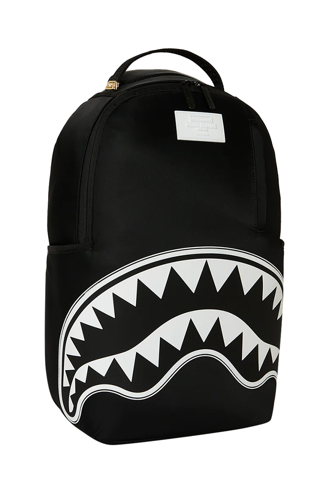 A black backpack featuring a large white shark mouth graphic on the lower front, with a top carry handle and a small white rectangular label near the top center.