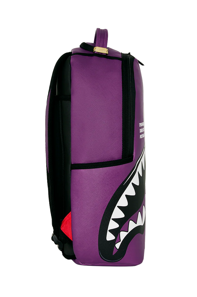 A purple and black duffel bag featuring a shark mouth graphic on the front, with white teeth and a small red accent near the bottom, shown against a plain white background.
