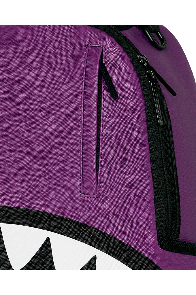 Close-up of a purple textured backpack with black zipper trim and a partial white-and-black shark-face graphic at the bottom.