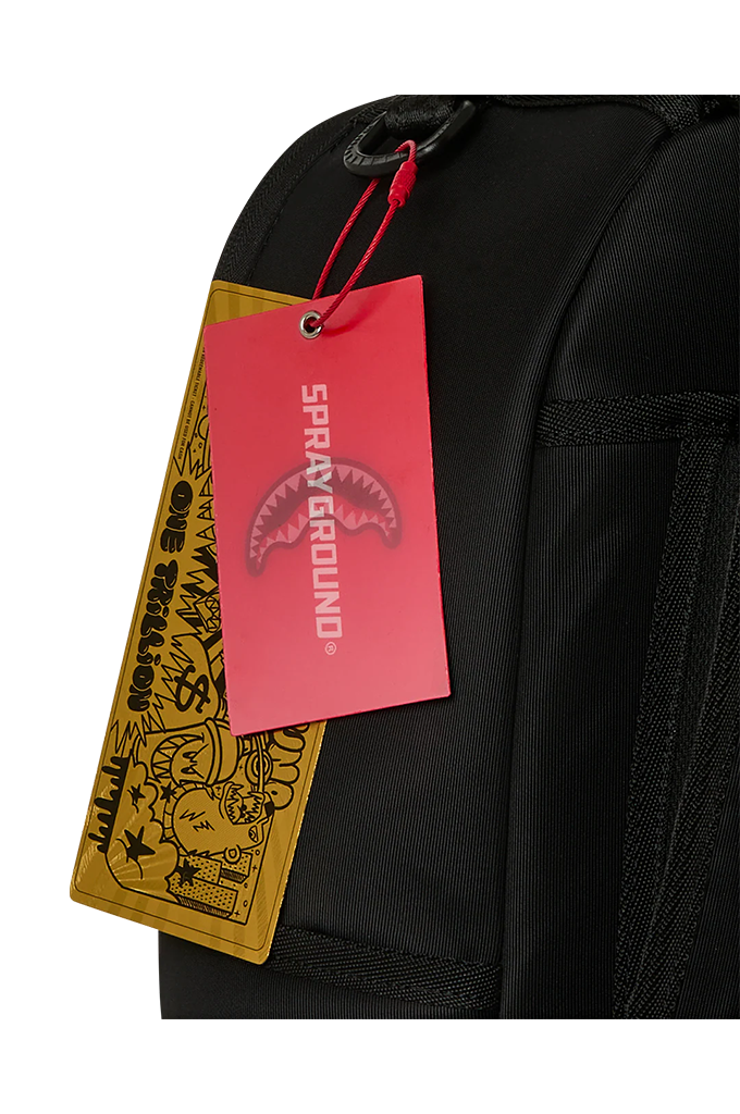 Close-up of a black backpack with a red and yellow Spray Ground hangtag attached near the top zipper area, on a white background.