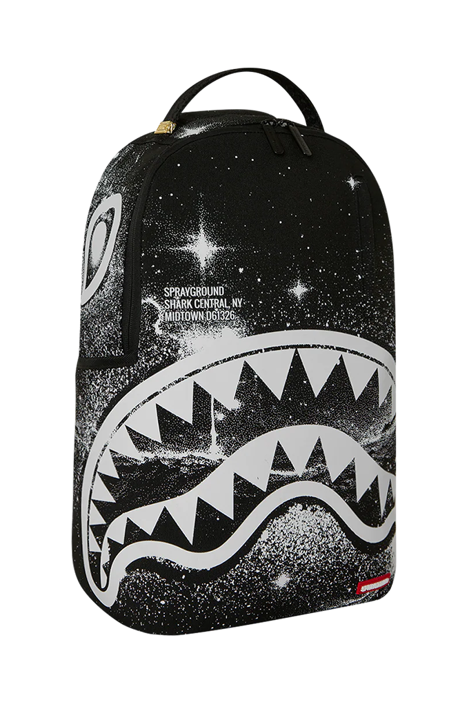 A black backpack featuring a white shark mouth graphic and a starry galaxy print, with the Sprayground logo and text on the front.