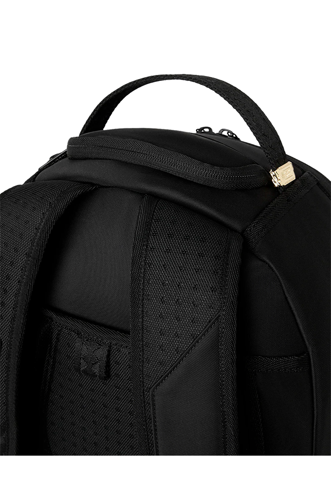 Close-up of a black backpack showing the padded shoulder straps, mesh ventilation panel, top zipper, and a small gold-tone metal accent on a white background.