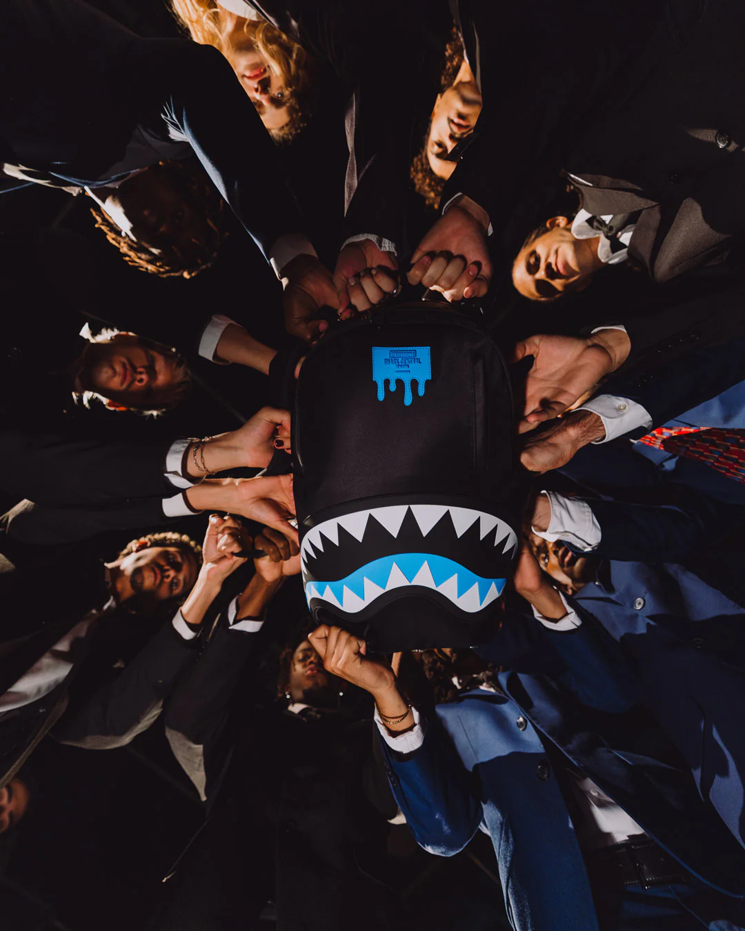 Group of people holding a black hoodie with a shark design in the center.