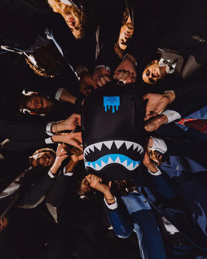 Group of people holding a black hoodie with a shark design in the center.