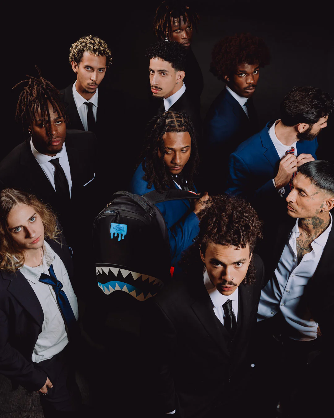Group of people in formal attire with a shark-patterned bag in the center.