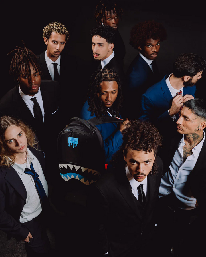 Group of people in formal attire with a shark-patterned bag in the center.