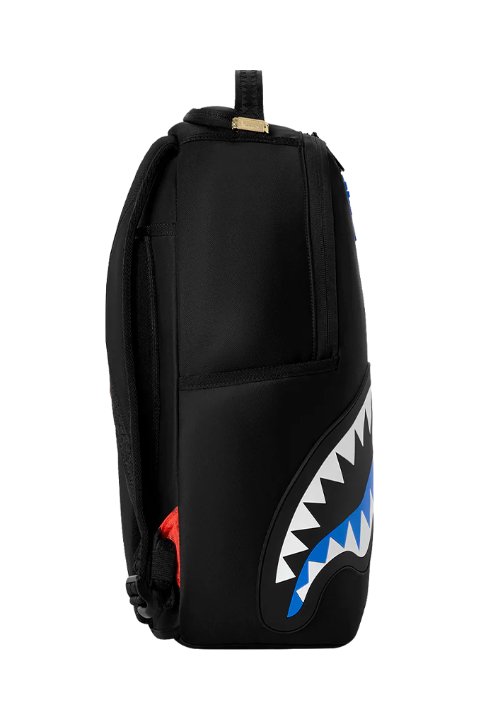 A black backpack featuring a large shark mouth graphic on the lower front, with white teeth, blue inner mouth details, and a small red accent on the side.