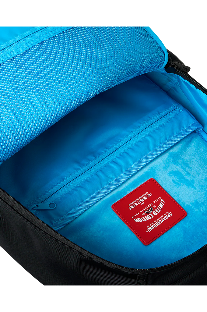 Close-up of the interior of a backpack showing a bright blue mesh lining, a zippered compartment, and a red rectangular brand patch with white text.