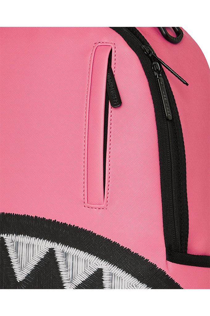 Close-up of a pink backpack featuring a black zipper pocket, black zipper track, and part of a black-and-white shark-mouth graphic at the bottom.