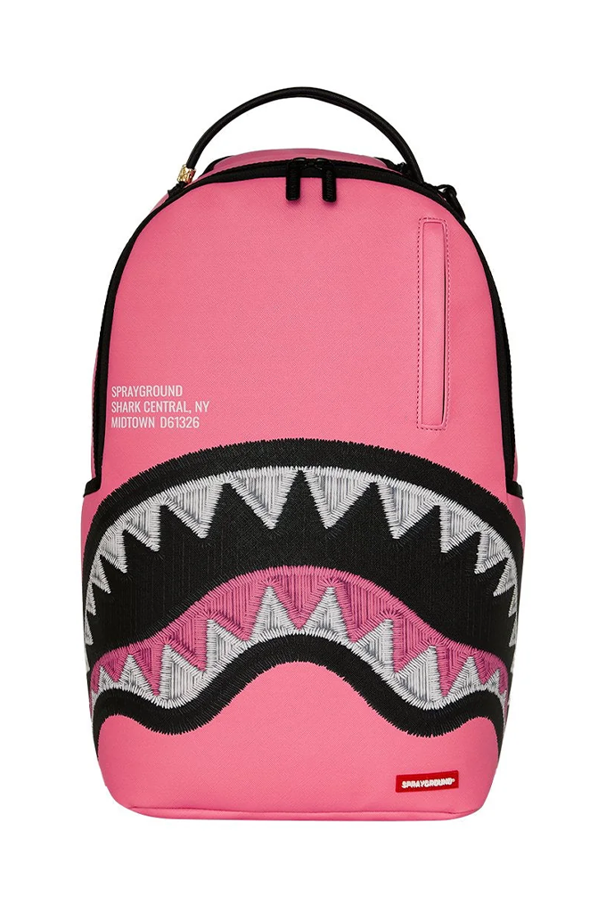 A pink Sprayground backpack featuring a shark mouth graphic with black, white, and pink details, on a white background.