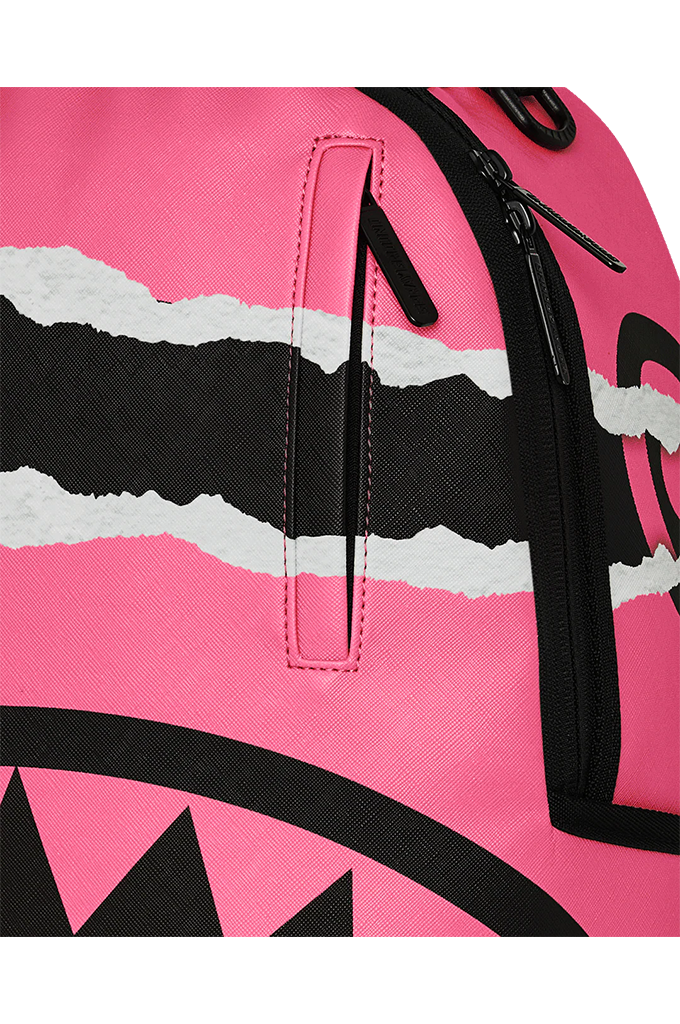 Close-up of a bright pink backpack featuring a black and white torn-paper graphic stripe and black zipper details.