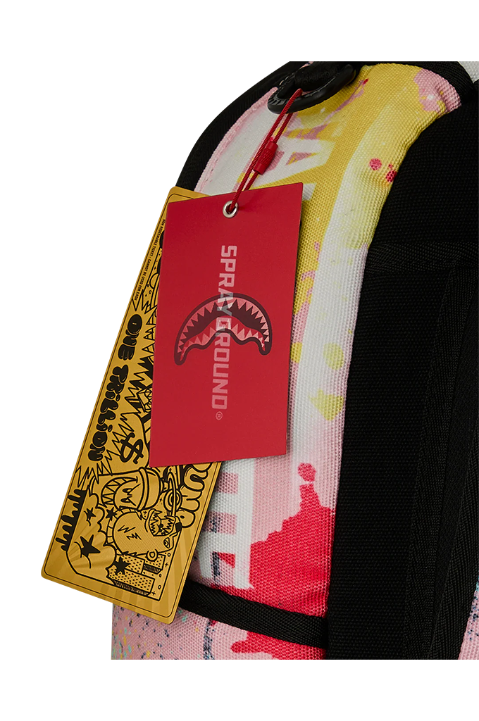Close-up of a colorful backpack with a red Sprayground hangtag and a yellow graphic tag, showing a pink, white, and yellow patterned fabric with black straps on a white background.