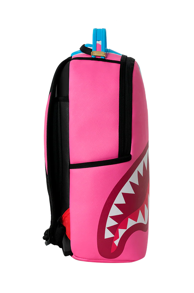 A bright pink backpack featuring a large shark mouth graphic on the lower right side, with black side straps and a blue top handle, shown against a plain white background.