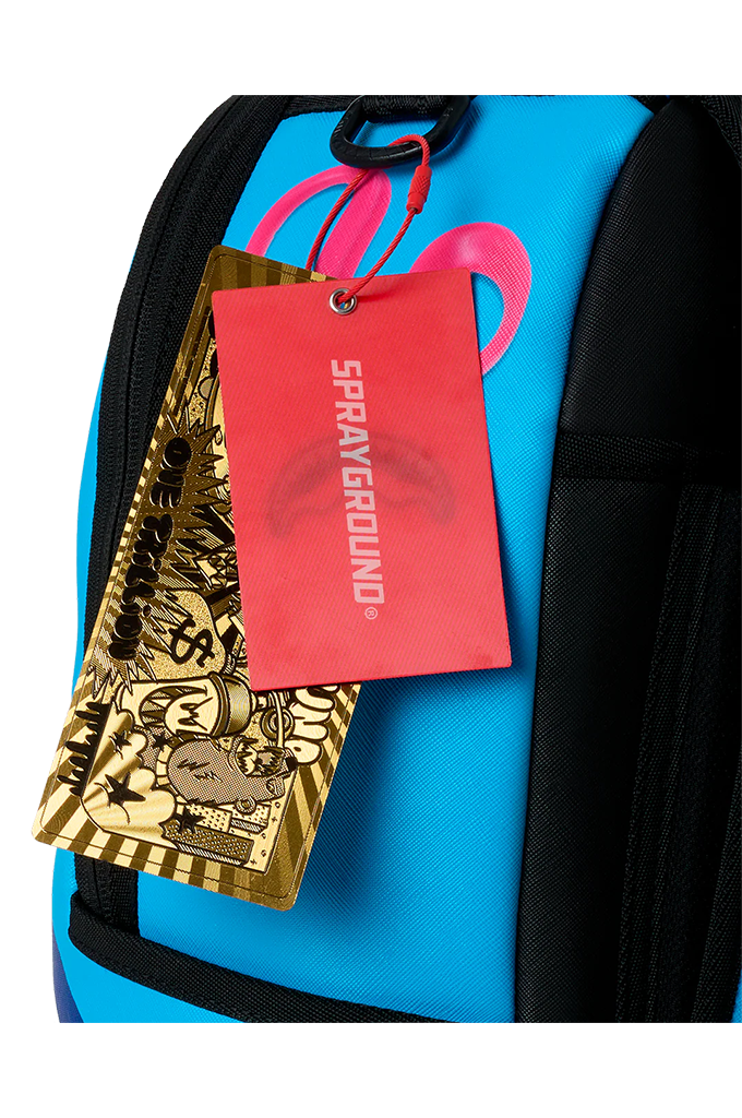 Close-up of a bright blue and black backpack with a red Sprayground hangtag and a gold patterned tag attached near the top zipper.