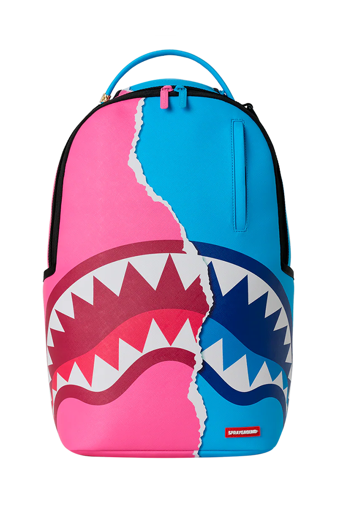 A Sprayground shark backpack in a vibrant pink and blue color-blocked design, featuring a large shark mouth graphic with white teeth across the lower half.