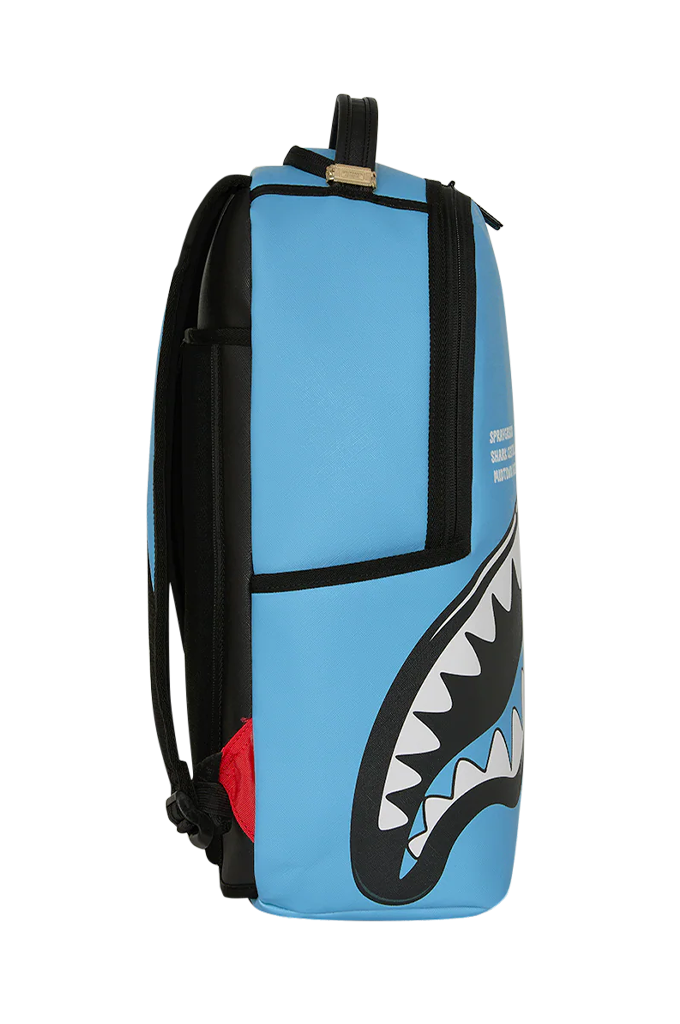 A light blue backpack featuring the iconic Shark Face graphic in black, white, and gray, with black straps and trim, and a small red accent on the side.