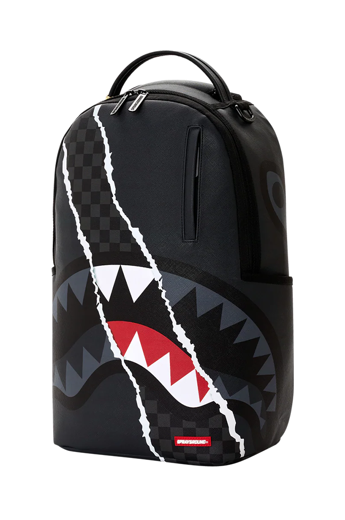 A black Sprayground backpack featuring a shark mouth graphic with white, red, and gray details, and a cracked white line design running vertically down the front.