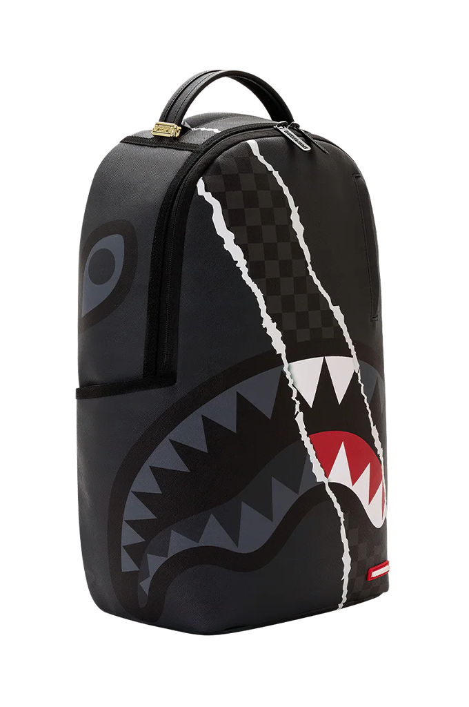 A black Sprayground backpack featuring a shark mouth graphic with white, red, and gray details, and a cracked white line design running vertically down the front.