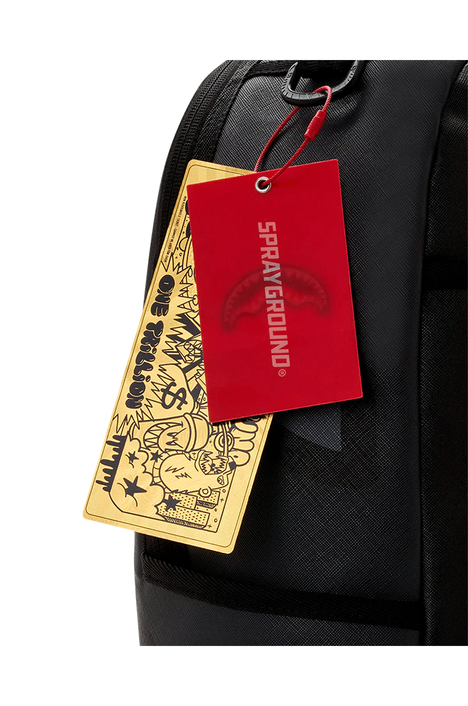 Close-up of a black backpack with two hanging tags: a bright red Sprayground tag and a gold-toned illustrated tag.