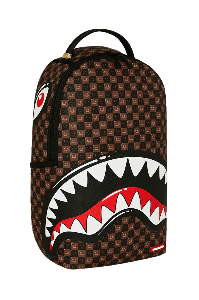 A Sprayground Shark backpack in brown and black checkered pattern with a large shark mouth graphic on the front, featuring white, red, and black details.