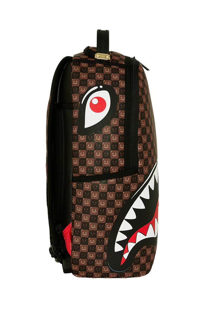A brown patterned backpack featuring a large shark-mouth graphic on the front with white, black, and red details, and a red circular eye motif on the upper side.