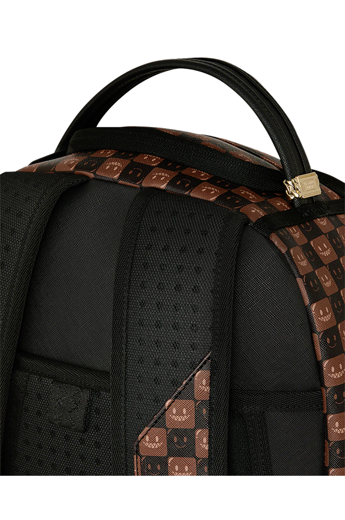 Close-up of a black backpack showing the top handle, padded shoulder straps, and brown patterned side panels with a repeating smiley face motif.