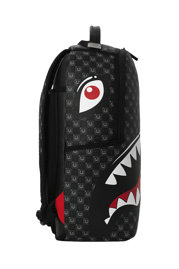 A black backpack featuring a repeating skull pattern, a large white eye graphic on the upper front, and a shark-mouth graphic on the lower front with white teeth and red accents.