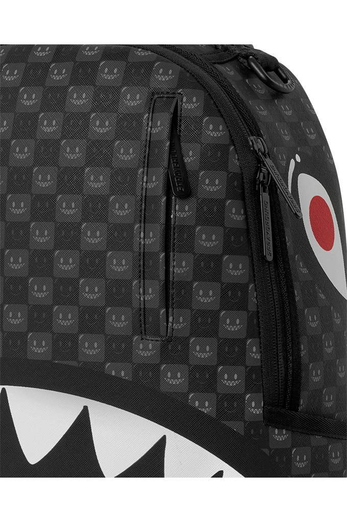Close-up of a black and gray patterned bag featuring a repeating shark-face motif, black zippers, and part of a white shark mouth graphic with a red circle on the right side.