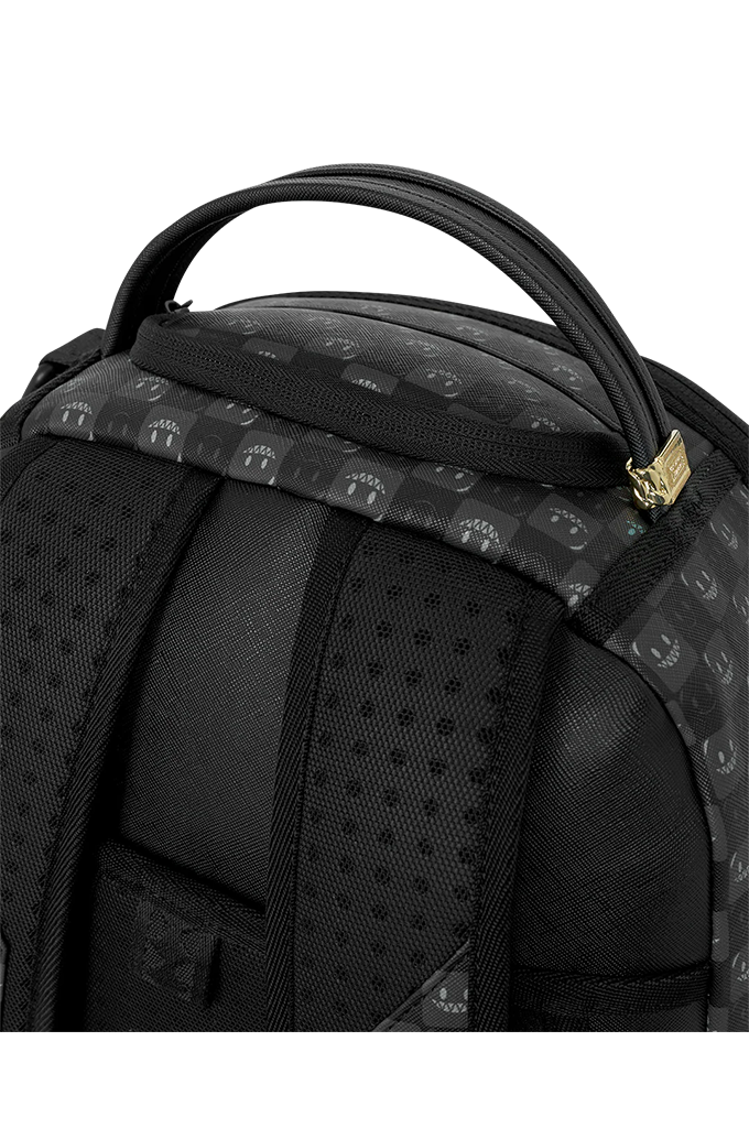 Close-up of a black backpack showing the top handle, padded shoulder straps, and a patterned fabric panel with a small gold zipper pull.