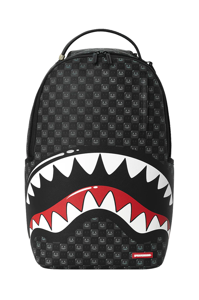 A black Sprayground shark backpack with a repeating smiley face pattern, featuring a large open mouth graphic with white teeth and red interior on the front, shown against a plain white background.