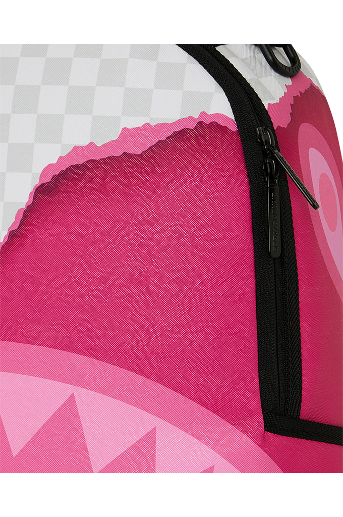 Close-up of a pink and white graphic backpack with a black zipper, showing a textured pink fabric, a white and gray checkerboard pattern, and a shark-mouth motif.