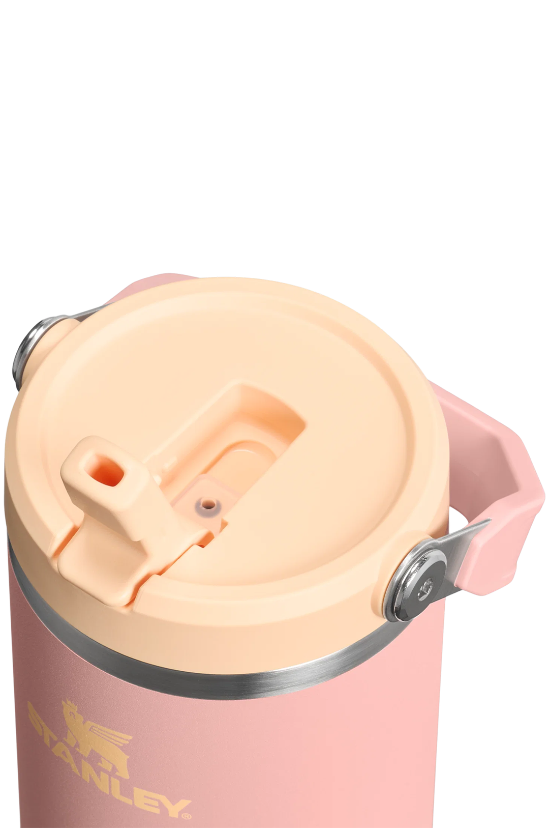 Close-up of a Stanley insulated tumbler with a light pink body, peach-colored lid, and a silver metal rim, featuring the gold Stanley logo.#color_peach-rose