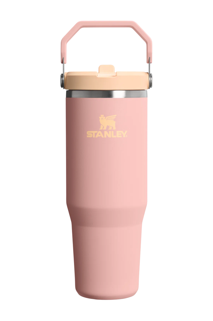A pink Stanley vacuum-insulated tumbler with a matching pink handle and a beige lid, shown on a solid white background.#color_peach-rose