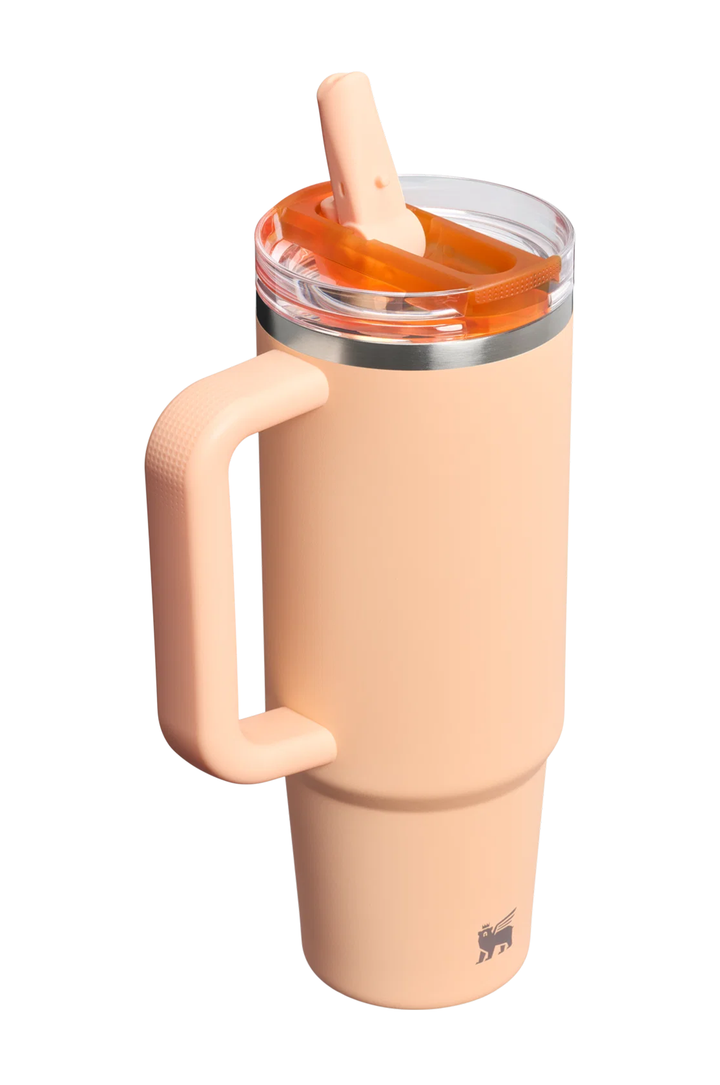 A peach-colored insulated travel tumbler with a matching handle, a clear lid, and an orange-tinted straw, shown on a solid white background.#color_orange-sherbet