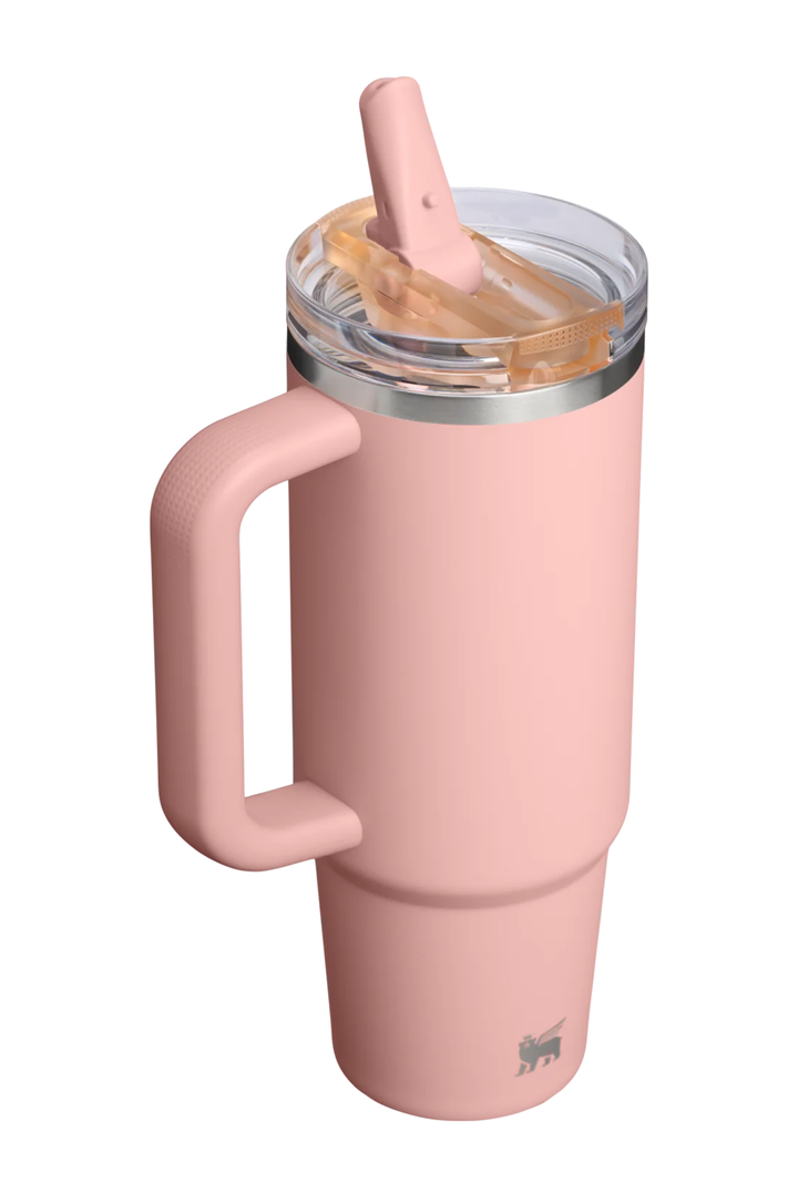 A dusty pink vacuum-insulated travel tumbler with a matching pink silicone handle and clear lid with a straw, shown on a solid white background.#color_peach-rose