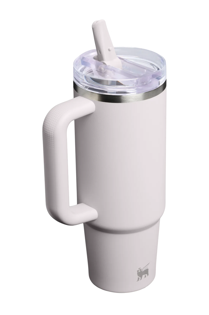 A matte white insulated travel tumbler with a large integrated handle, a clear lid with a white straw, and a silver metal band near the top. A small gray deer logo is visible near the bottom.#color_sahara