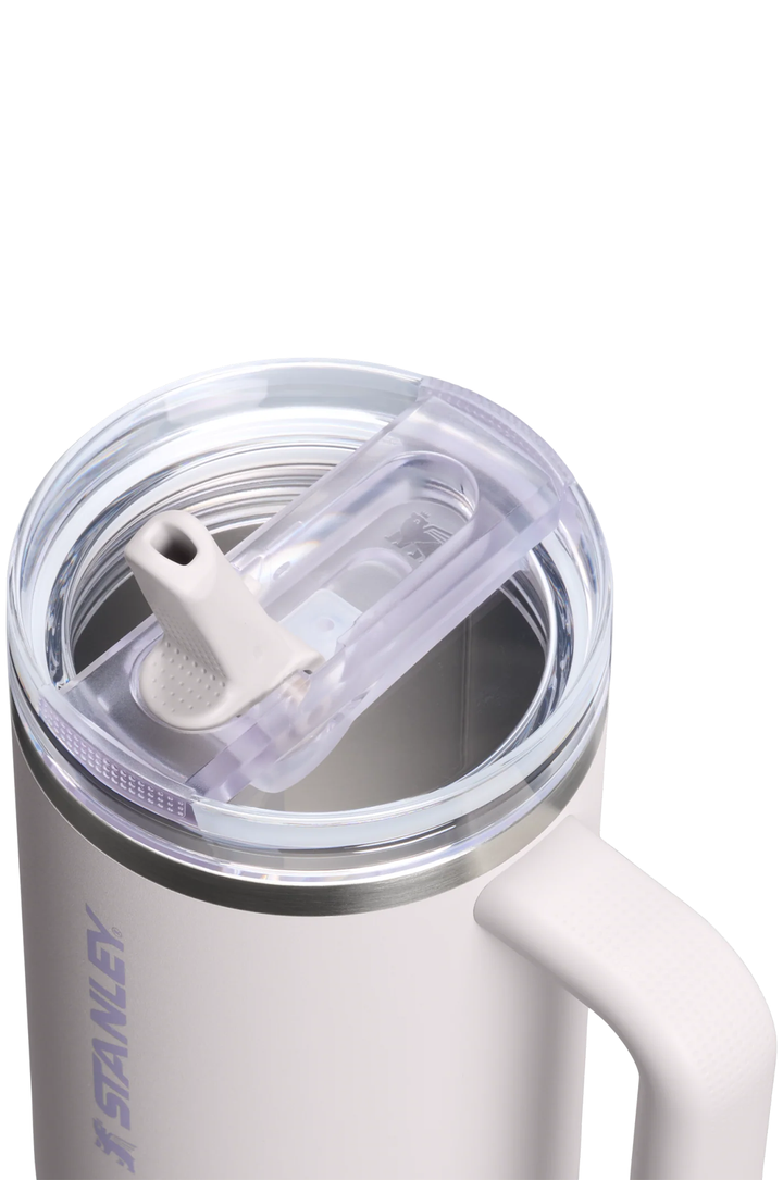 Close-up of a white Stanley insulated tumbler with a clear lid and flip-top straw, showing the Stanley branding on the side against a white background.#color_sahara
