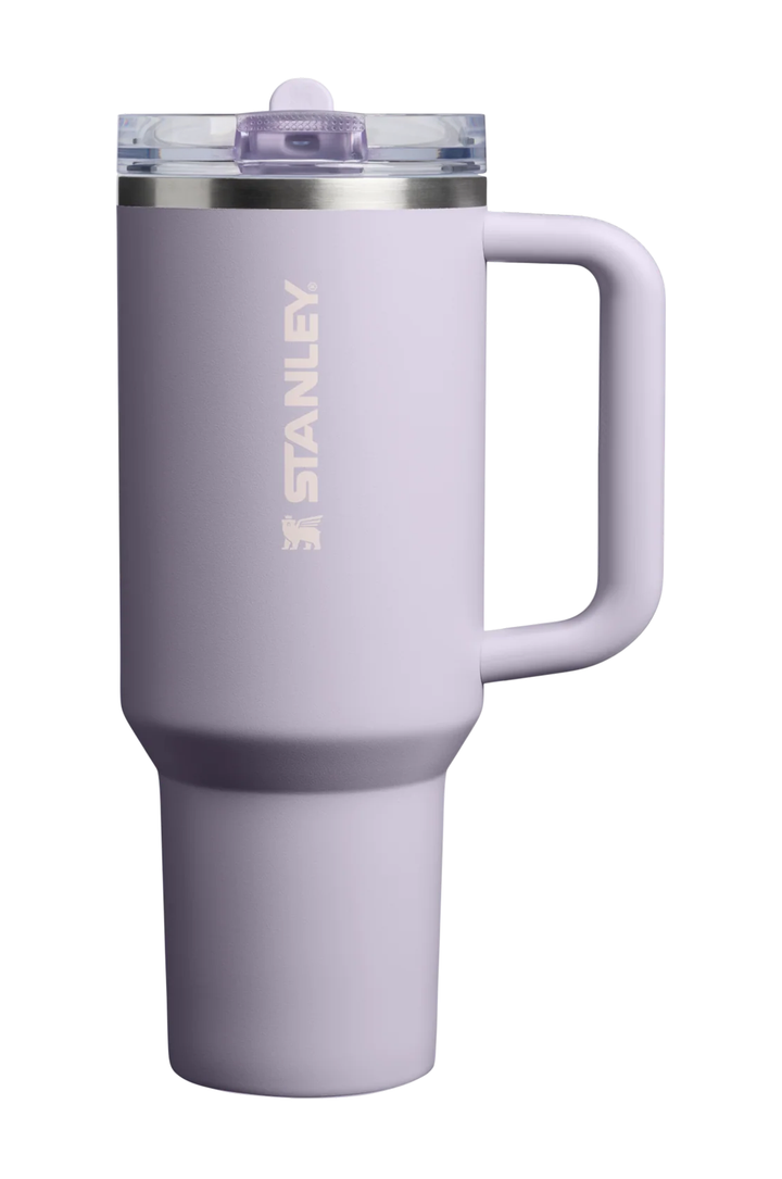 A lavender purple Stanley travel mug with a handle, a clear lid, and a silver rim, shown on a solid white background.#color_purple-dust