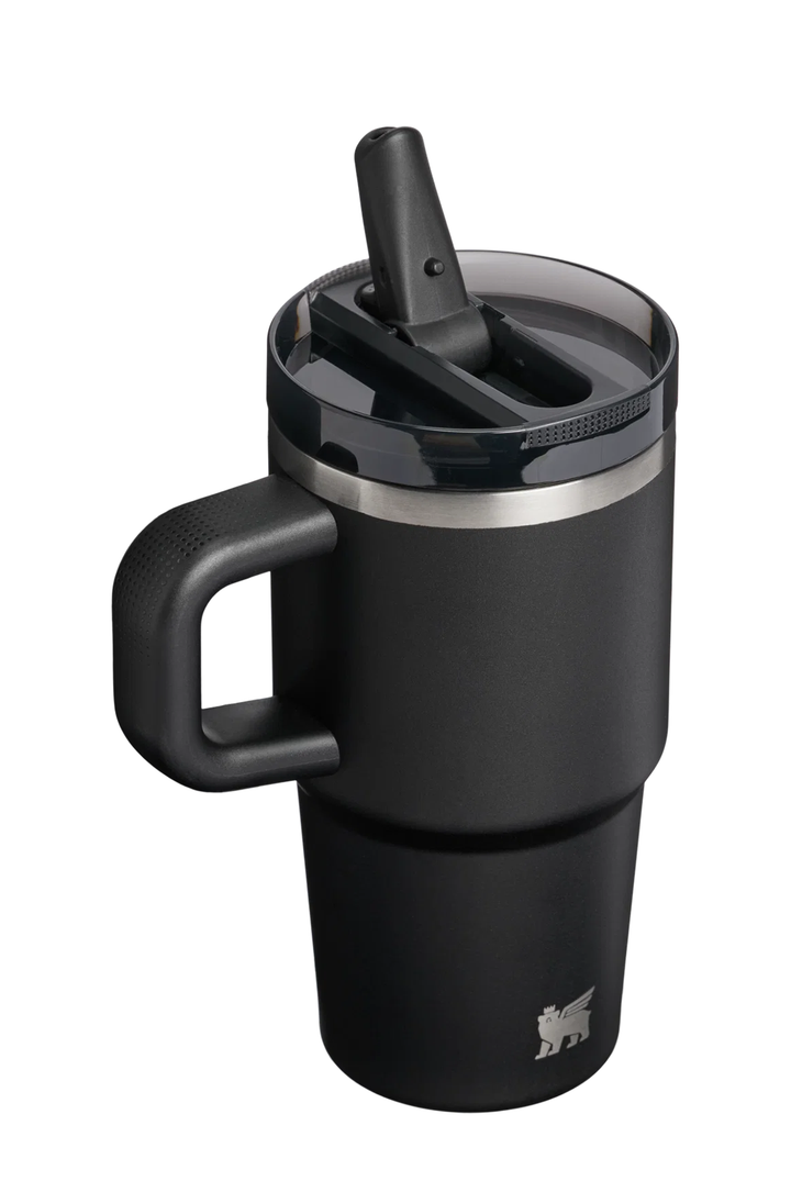 A matte black insulated travel tumbler with a matching black handle and lid, featuring a clear lid with a black flip-up straw and a silver metallic band near the top. A small silver lion logo is visible near the bottom right.#color_black