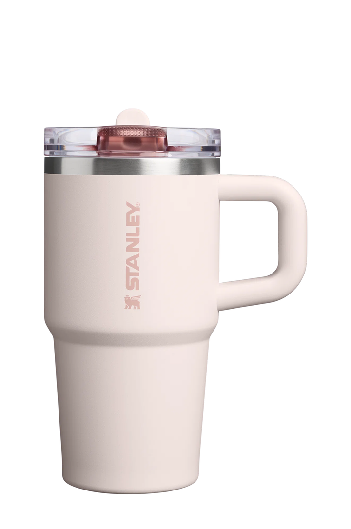 A pale pink Stanley travel mug with a matching handle, a clear lid, and a rose gold logo printed vertically on the side, set against a plain white background.#color_rose-quartz